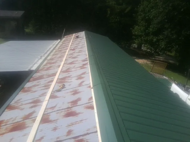 Old rusted panels beside newly installed green metal roofing — Wind Damage Roof Repair by Roofing Brothers in Rock Hill