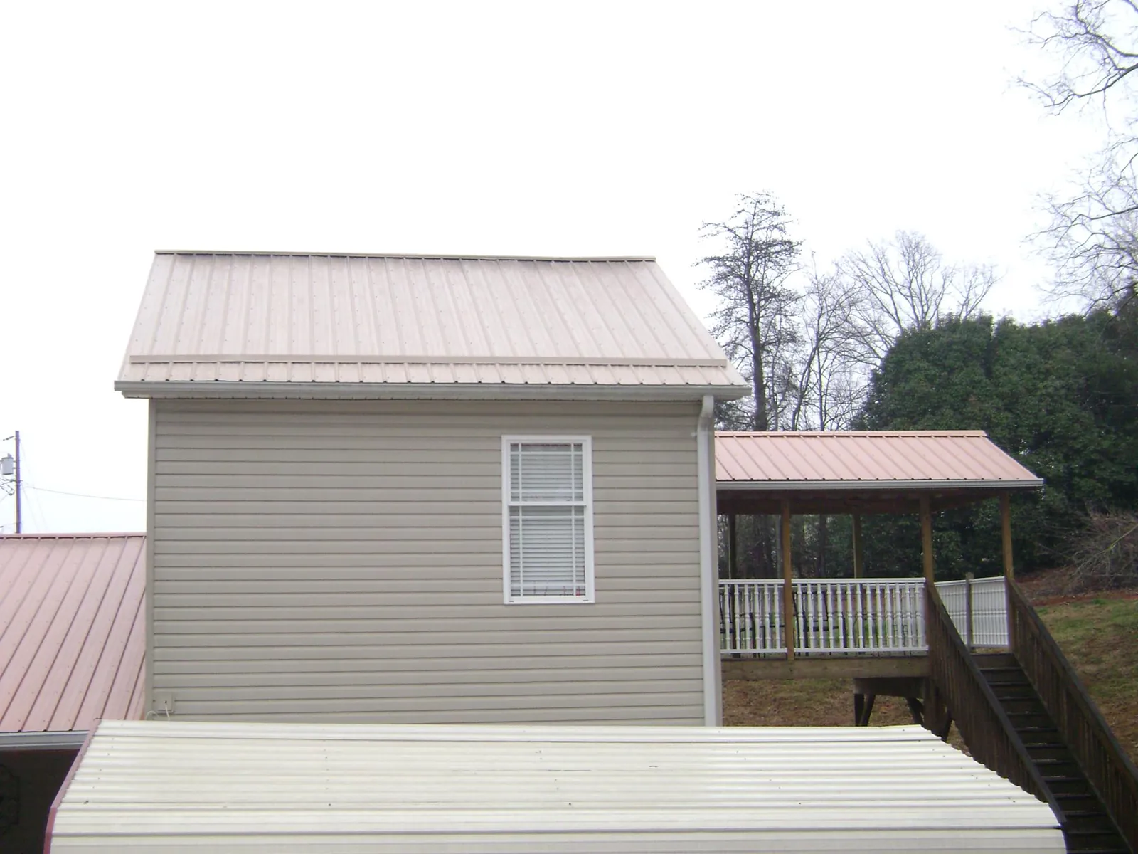 Tan metal roofs on a two story addition and attached porch, from a Roof Replacement job in Rock Hill